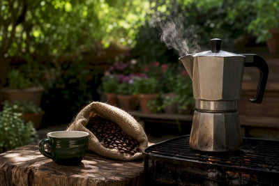 Moka pot steaming next to espresso machine portafilter and cup