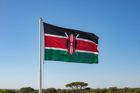 Kenyan flag waving against clear blue sky with acacia trees in background representing Kenya origin of medium roast coffee