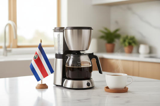lifestyle picture with a coffee maker on a kitchen counter with a half filled coffee pot with the costa rica flag on one side and a cup of brewed coffee on the other side